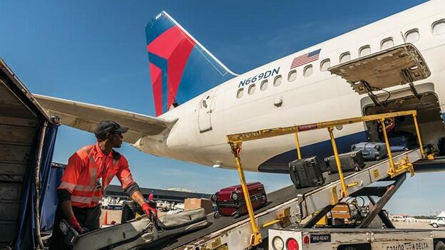 A Delta employee loads baggage onto a plane.