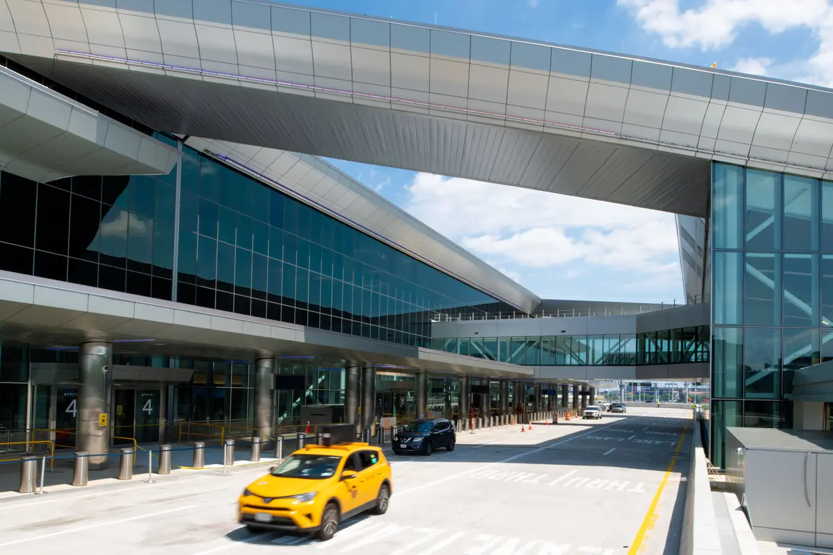 Exterior view of Delta's terminal at LaGuardia, daytime. Yellow cab in foreground