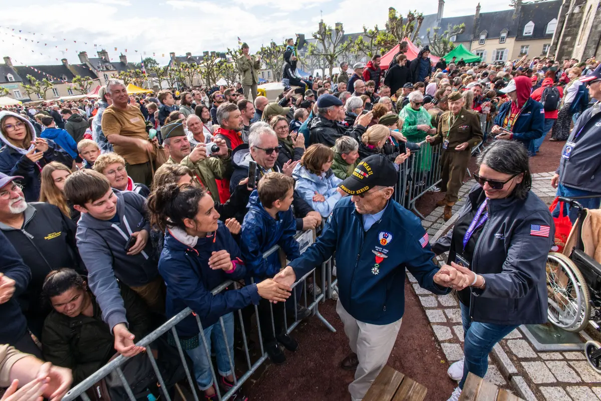 Delta’s Carmela Carter escorts World War II veteran Wally King through a parade in St. Mere Eglise.