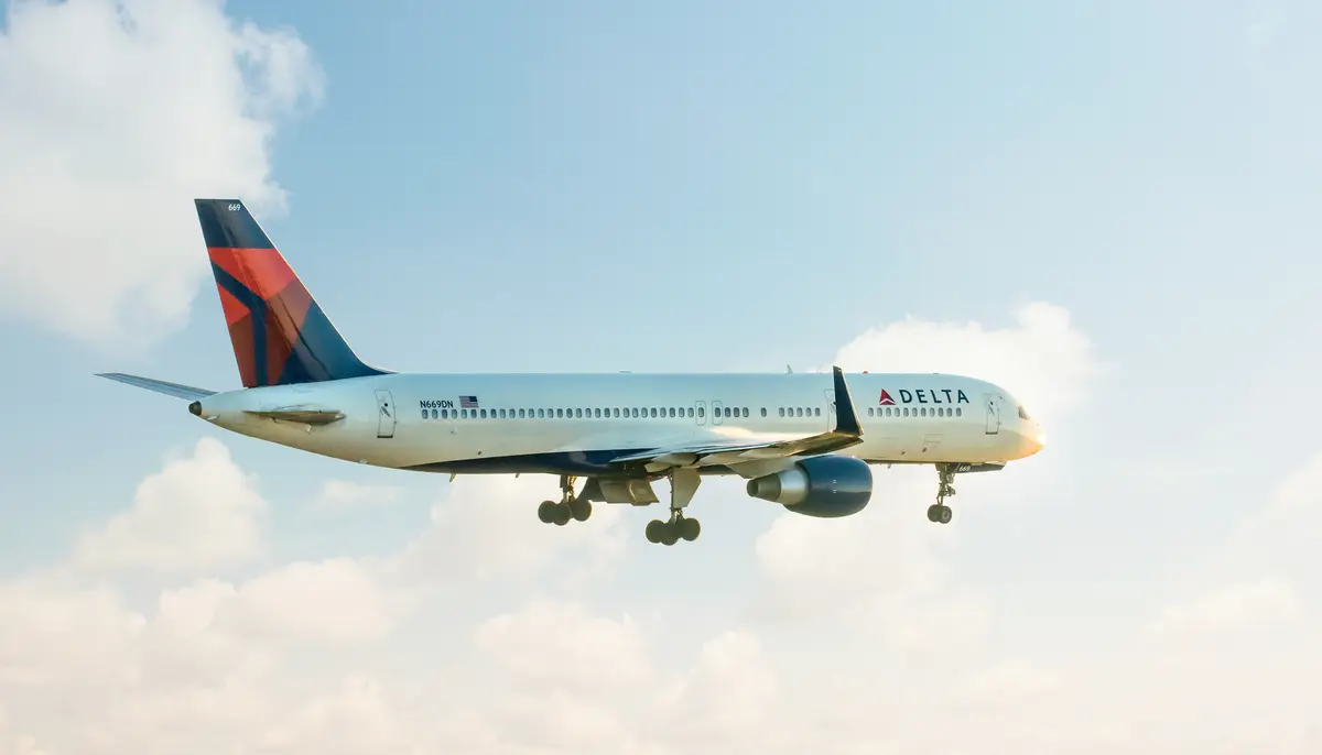 A 757-200 takes off for departure into a clouded sky.
