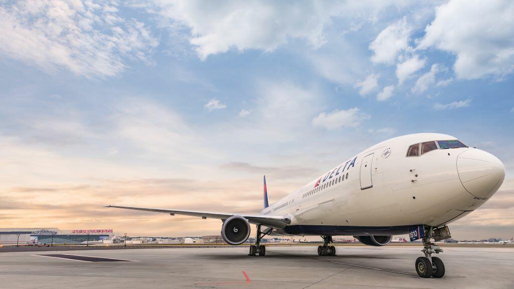 A frontal view of Delta's Boeing 767-400 model sits on the runway while a wisped sky overlooks. 