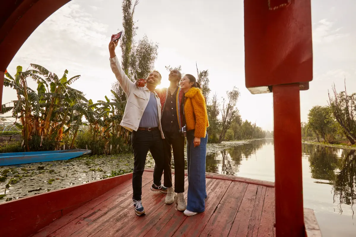 Three people take a selfie on a Mexican trajinera.