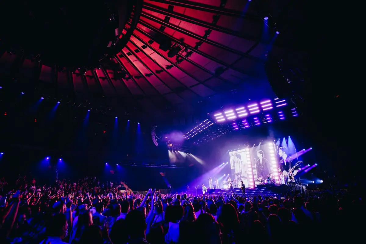 Jonas Brothers concert with full crowd in stadium and bright lights on the stage.