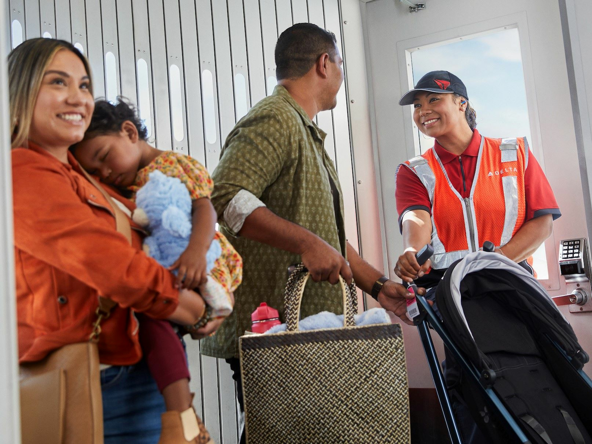 A Delta ACS employee helps a family with their stroller on the jet bridge.