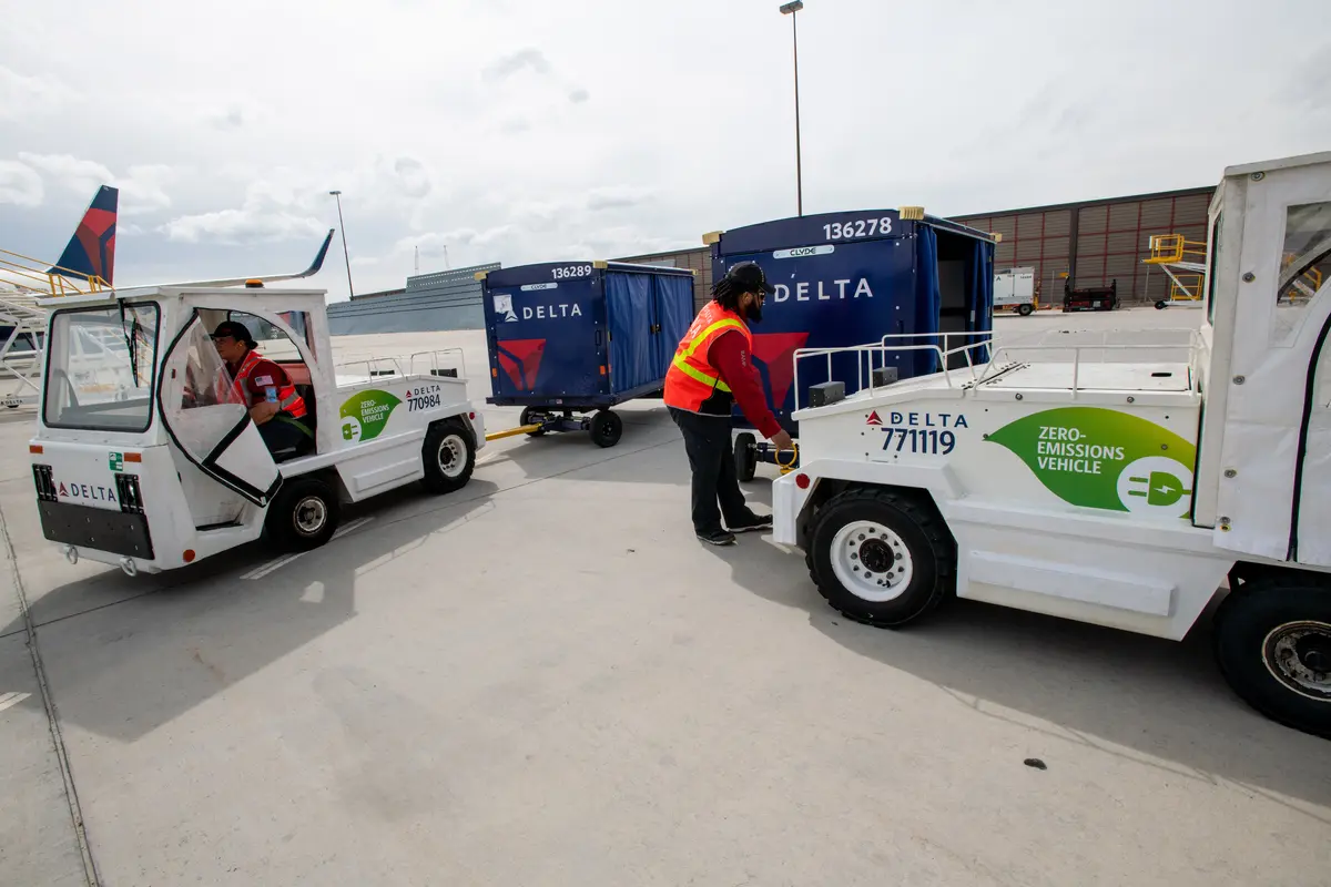 Delta Ramp Agent Sinai Pauni (left) and Aircraft Load Agent Thomas Tuikolovatu (right) operate electric bag tractors at Salt Lake City International Airport (SLC).