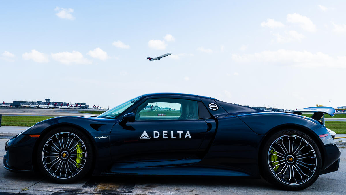 A Delta Boeing 717 takes off above a Porsche 918 Spyder at Hartsfield-Jackson Atlanta International Airport.