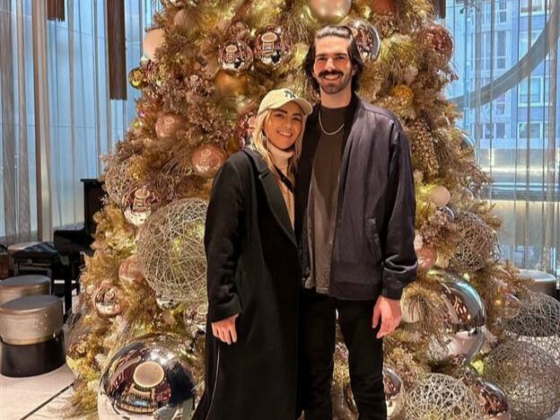 Delta customers Paige and Ian, who met in a Delta Sky Club, pose in front of a Christmas tree.