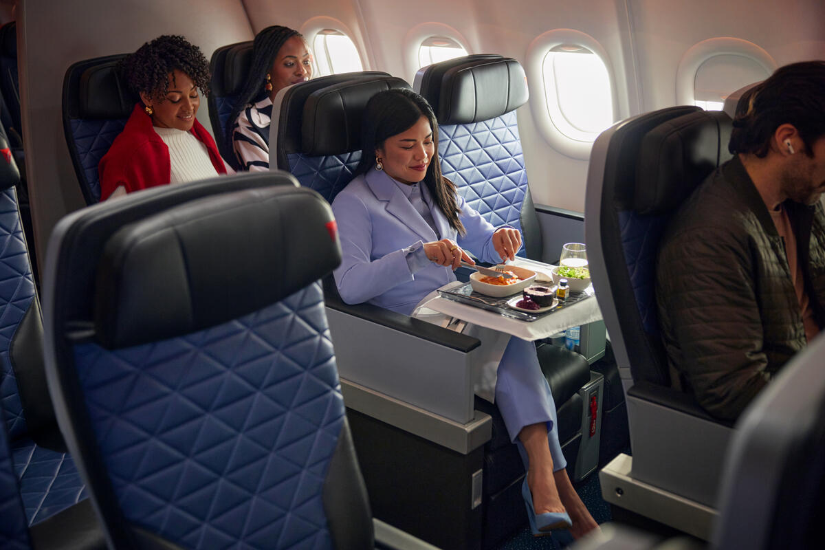 A Delta customer seated in Delta Premium Select enjoys a meal.