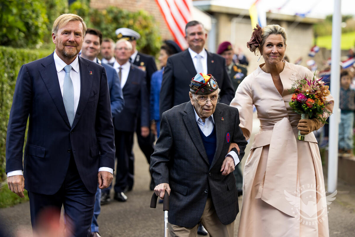 One of the six U.S. veterans that Delta flew to commemorate the liberation of the Netherlands walks with the King and Queen of the Netherlands.