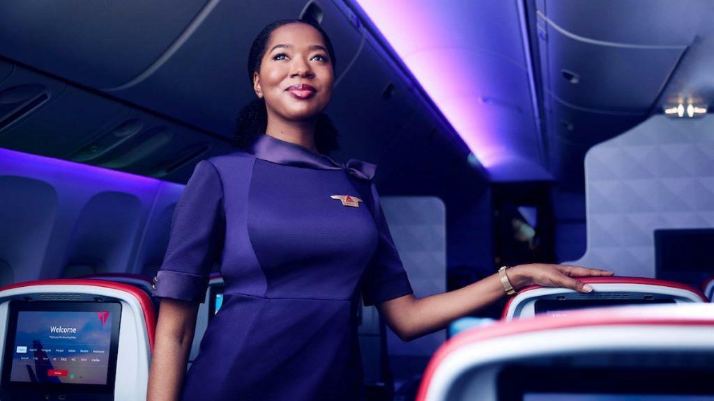 A Delta flight attendant stands in the row of a cabin