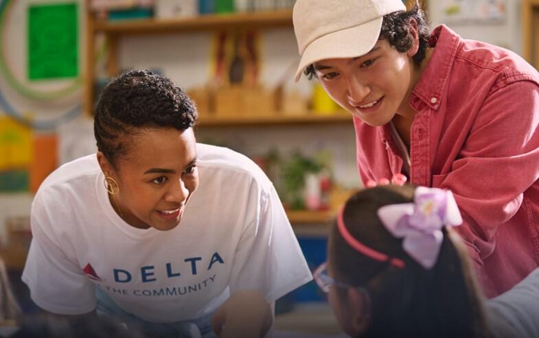 Delta employee volunteer smiling while interacting with a young girl.
