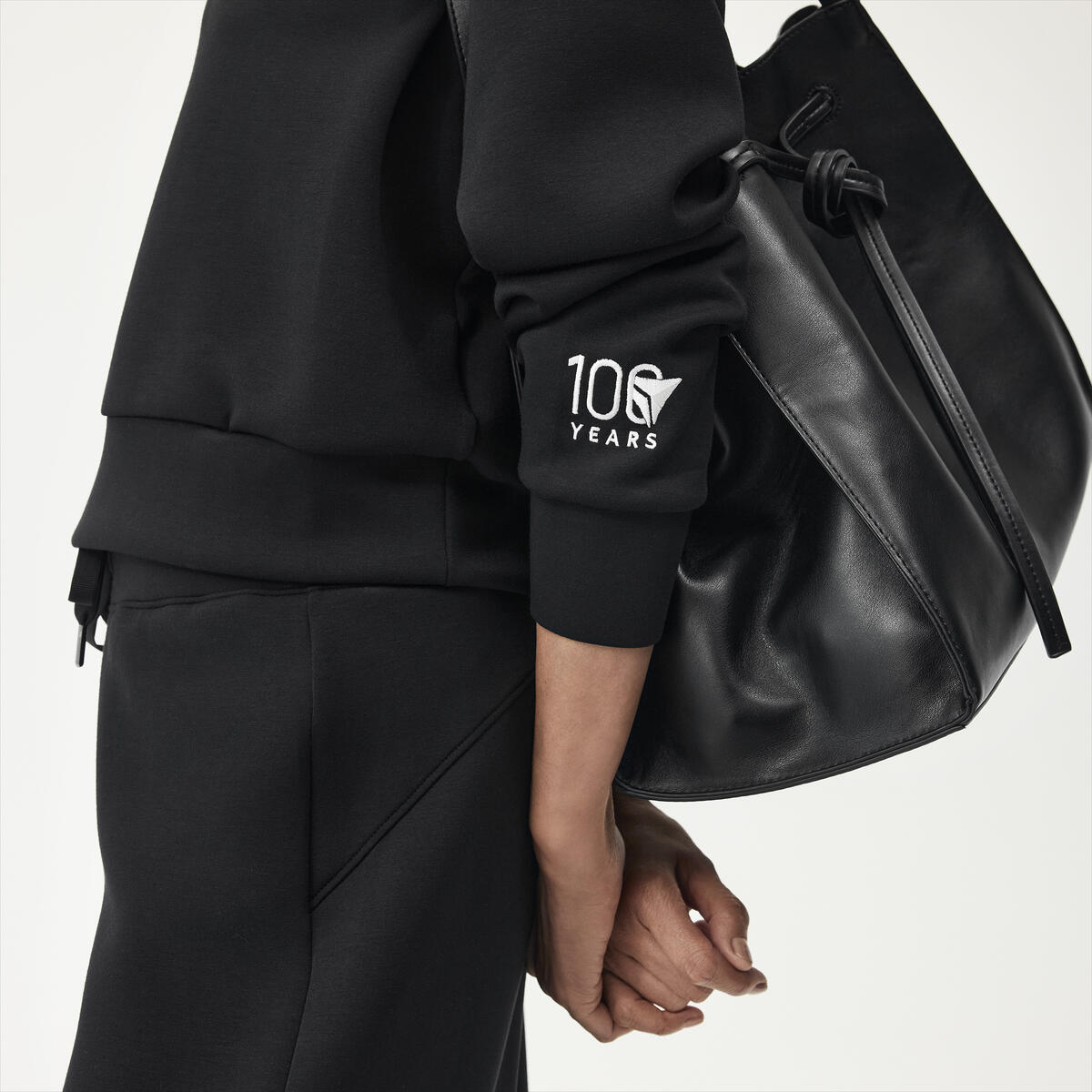 Profile shot of woman wearing black spanx outfit embroidered with Delta Centennial logo.