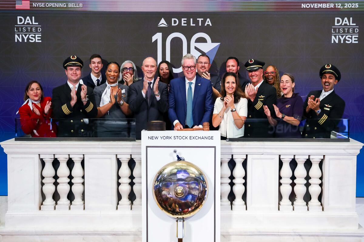 Ed standing in front of the NYSE bell with a group of employees, all clapping