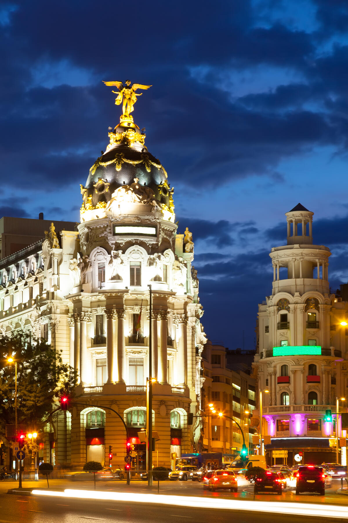 Illuminated domed building at a busy city intersection during dusk.