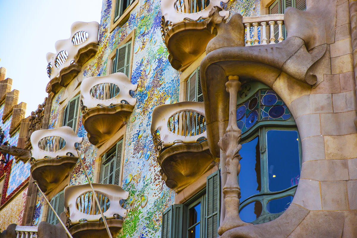Colorful, organic-shaped balconies and windows on a decorative, mosaic-covered building façade.