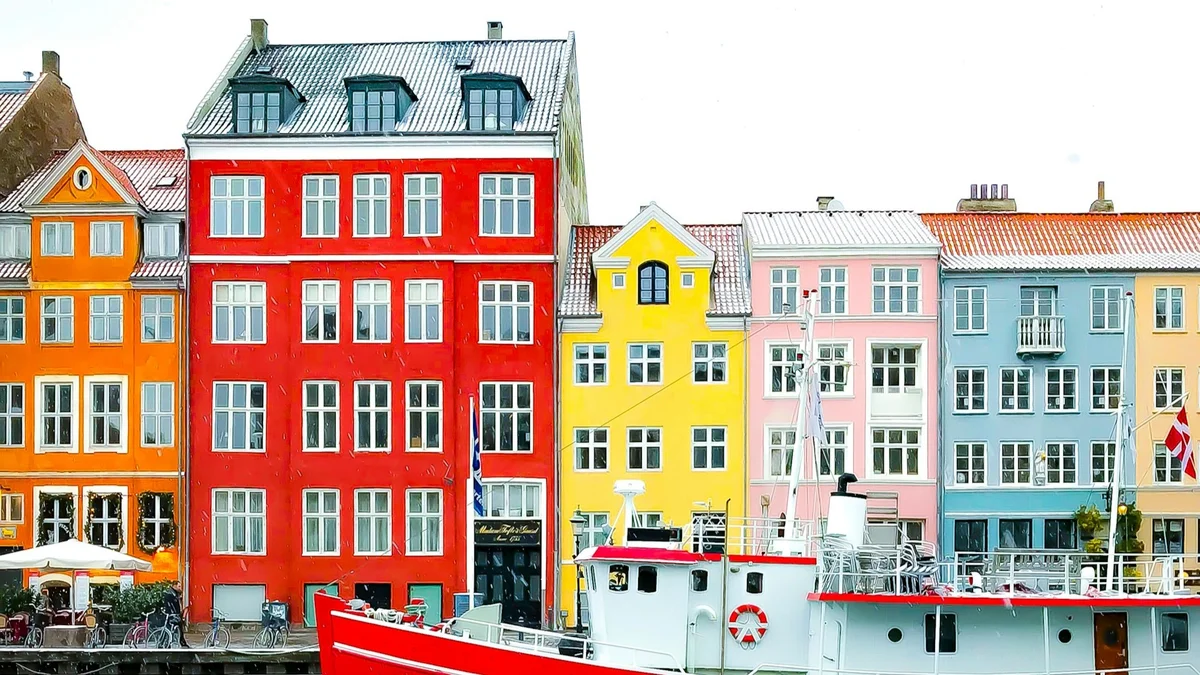 Nyhavn district with boats on water canal and colorful row of old houses in Copenhagen, Denmark