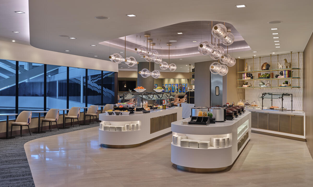Modern buffet area with curved food stations, hanging globe lights and seating along large windows