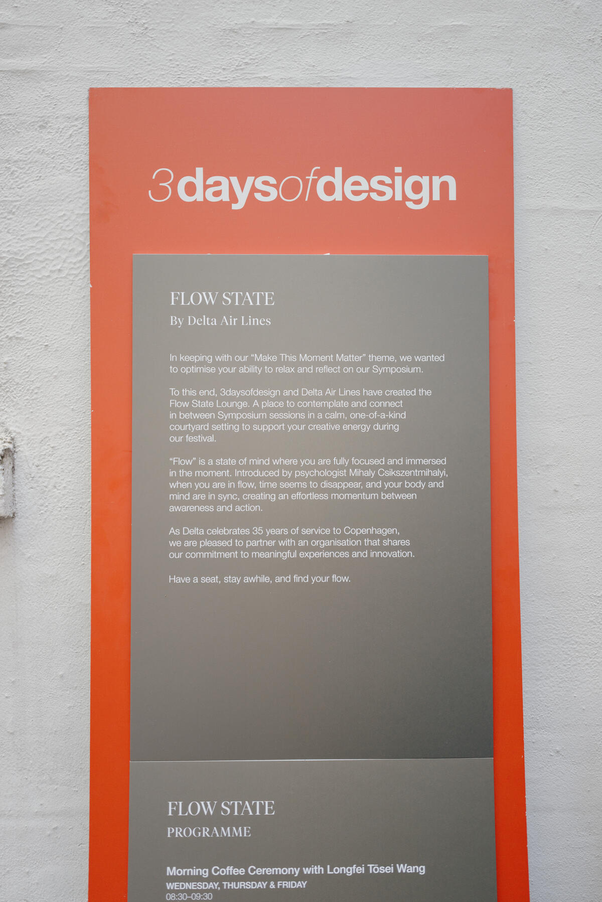Poster on a wall reading “3daysofdesign” with a “Flow State by Delta Air Lines” description and event program details below.