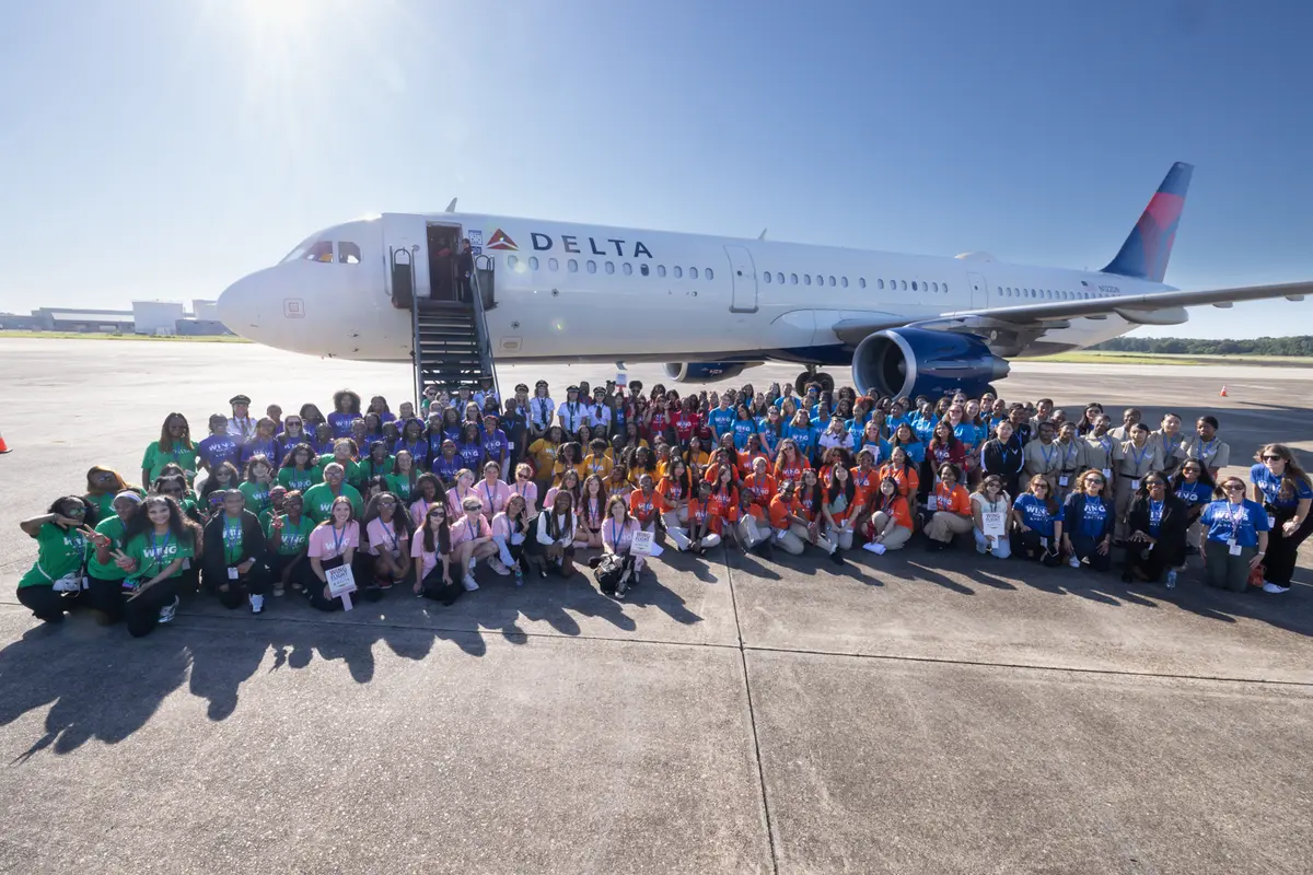 Large group of WING Flight participants gathered on the tarmac in front of a Delta aircraft during Girls in Aviation Day.