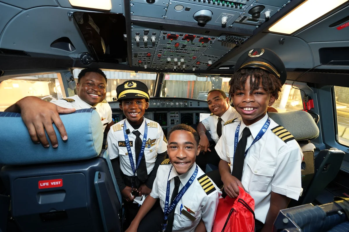 DREAM Flight participants pose with flight crew members in an aircraft cockpit during a behind-the-scenes aviation experience.
