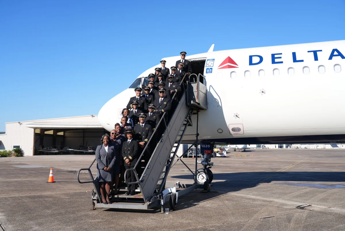 Delta pilots and employees pose on the boarding stairs of a Delta aircraft during the 26th annual DREAM Flight at Airbus’ Mobile, Alabama facility.