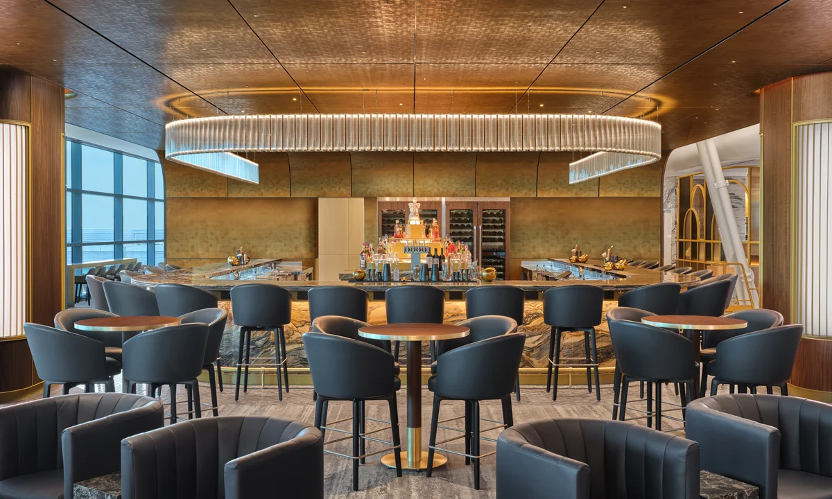 Upscale airport lounge bar with modern seating, marble accents, and a large illuminated chandelier overhead.