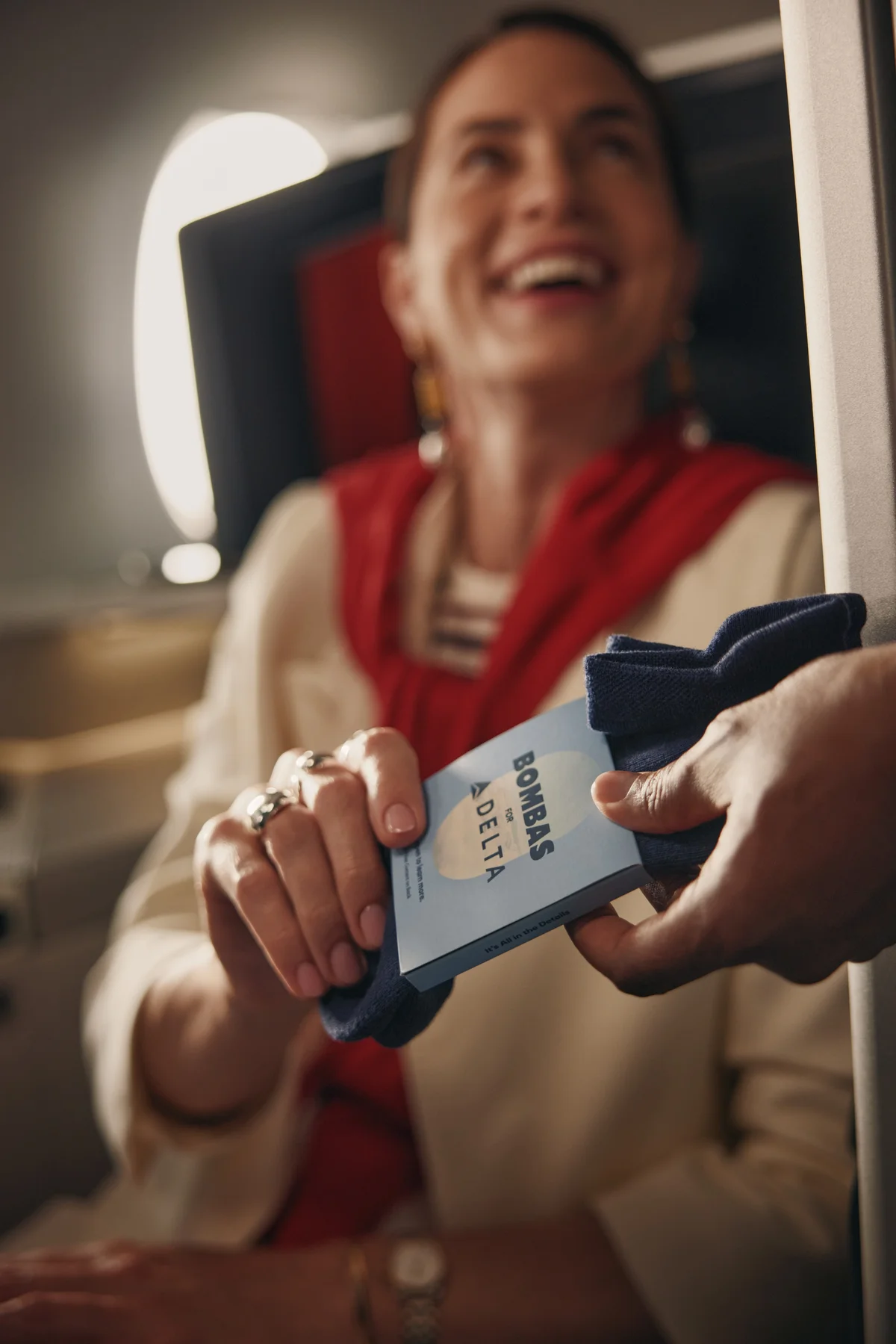 Customer receives a pair of Bombas socks while seated in a Delta One suite.
