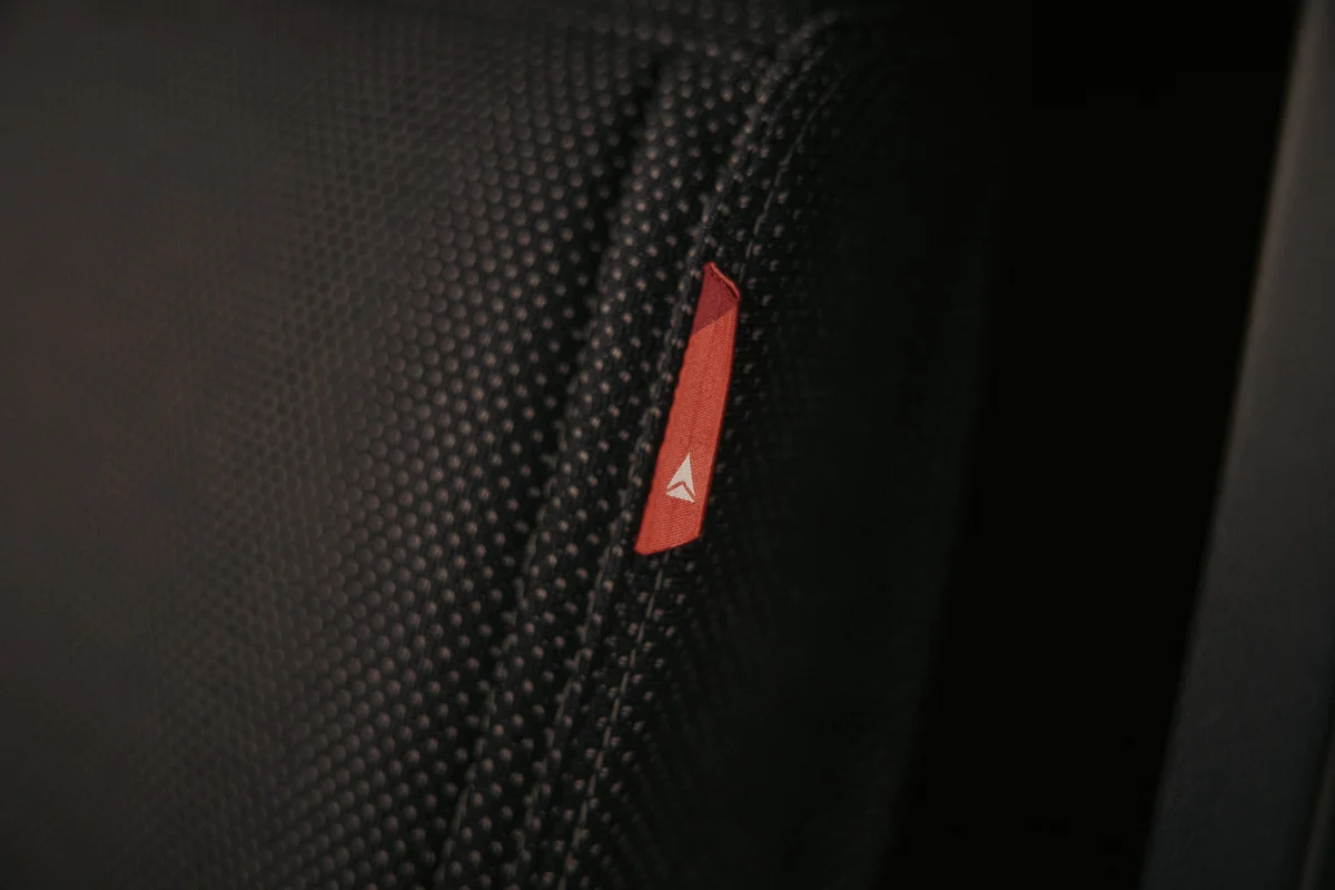 Close-up of a textured black seat surface featuring a small red Delta-branded fabric tag.