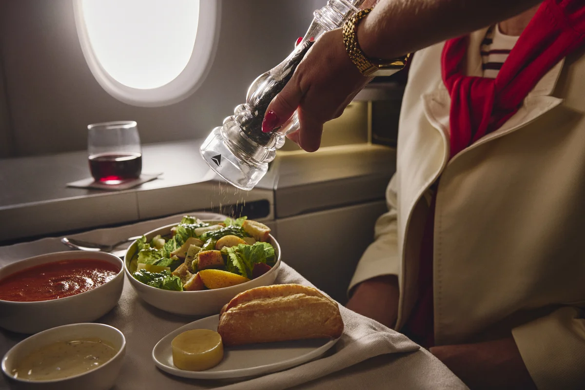 Fresh salad, soup, bread, and wine served on a Delta One dining tray table.