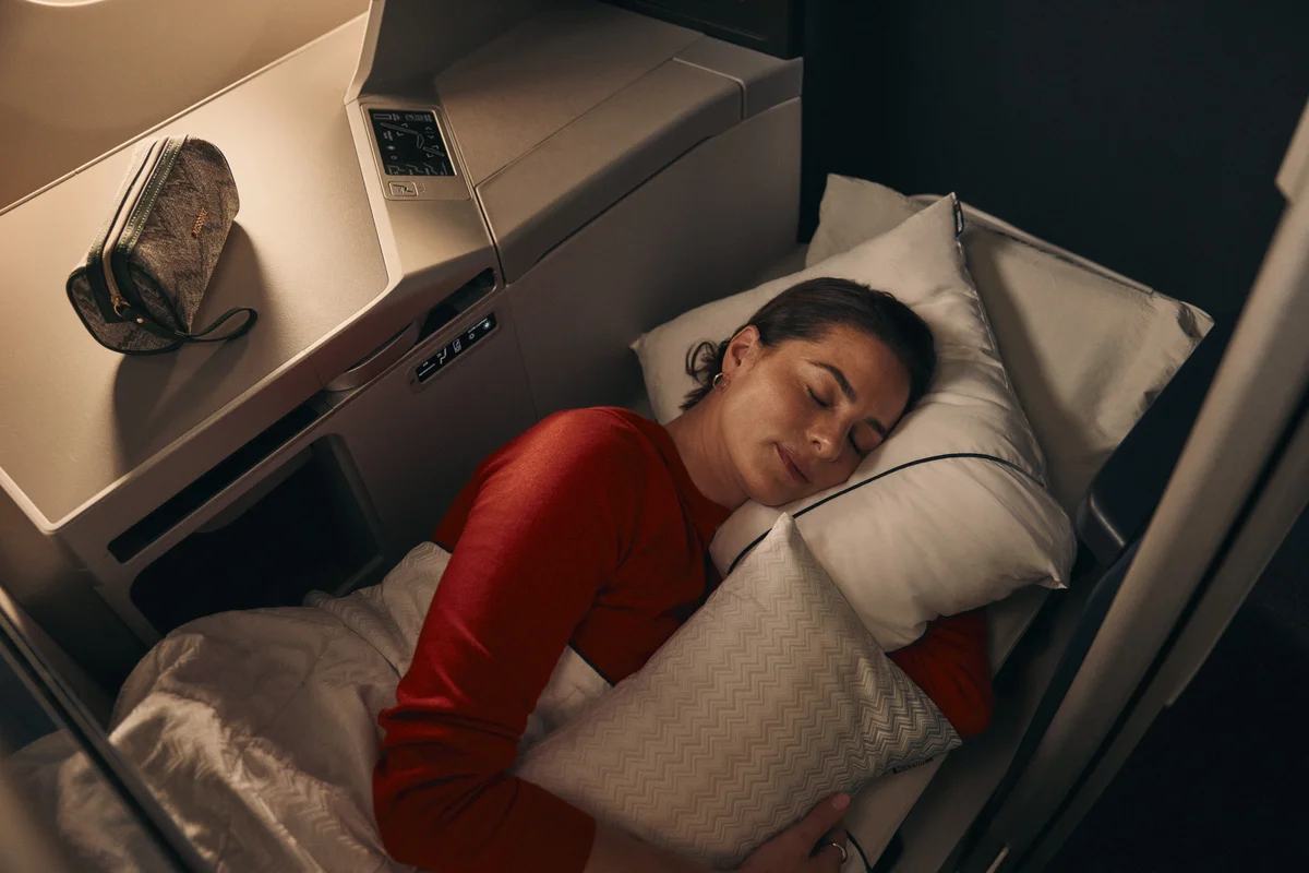 Customer resting in a lie-flat Delta One suite with bedding and pillow.