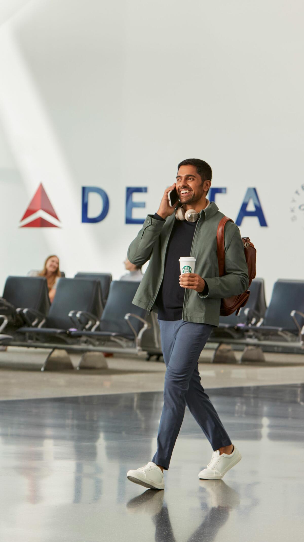 Delta customer en route through airport enjoying Starbucks beverage