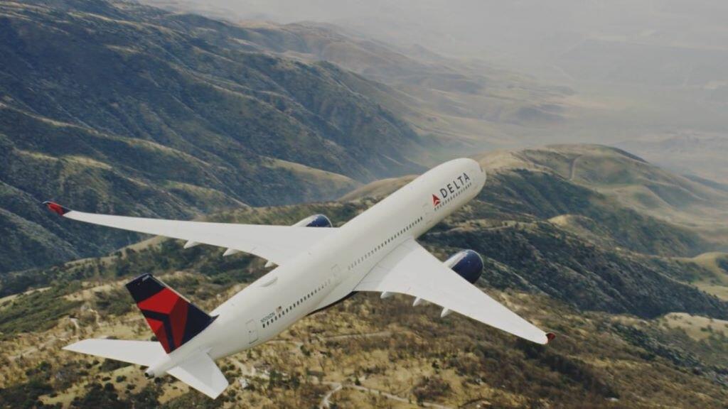 An A350 Delta aircraft flies over mountains