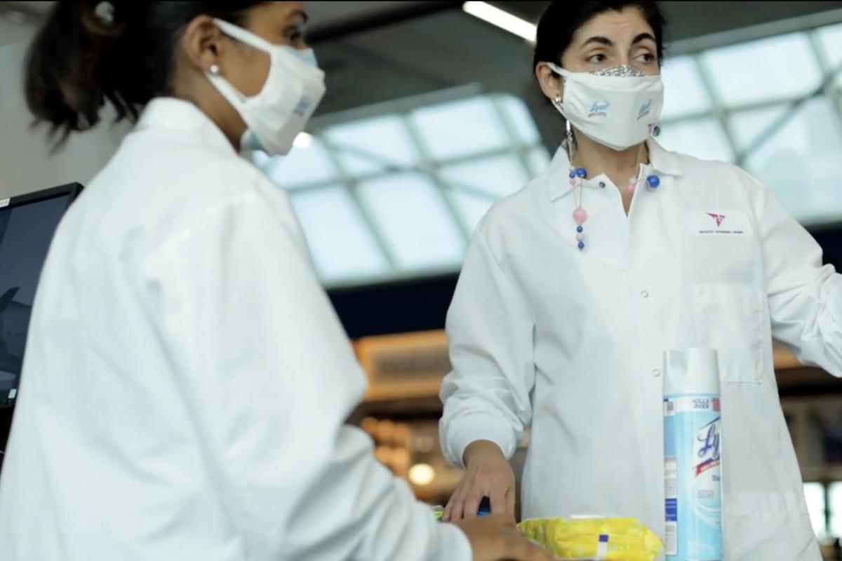 Two women in PPE using Lysol in the LaGuardia airport