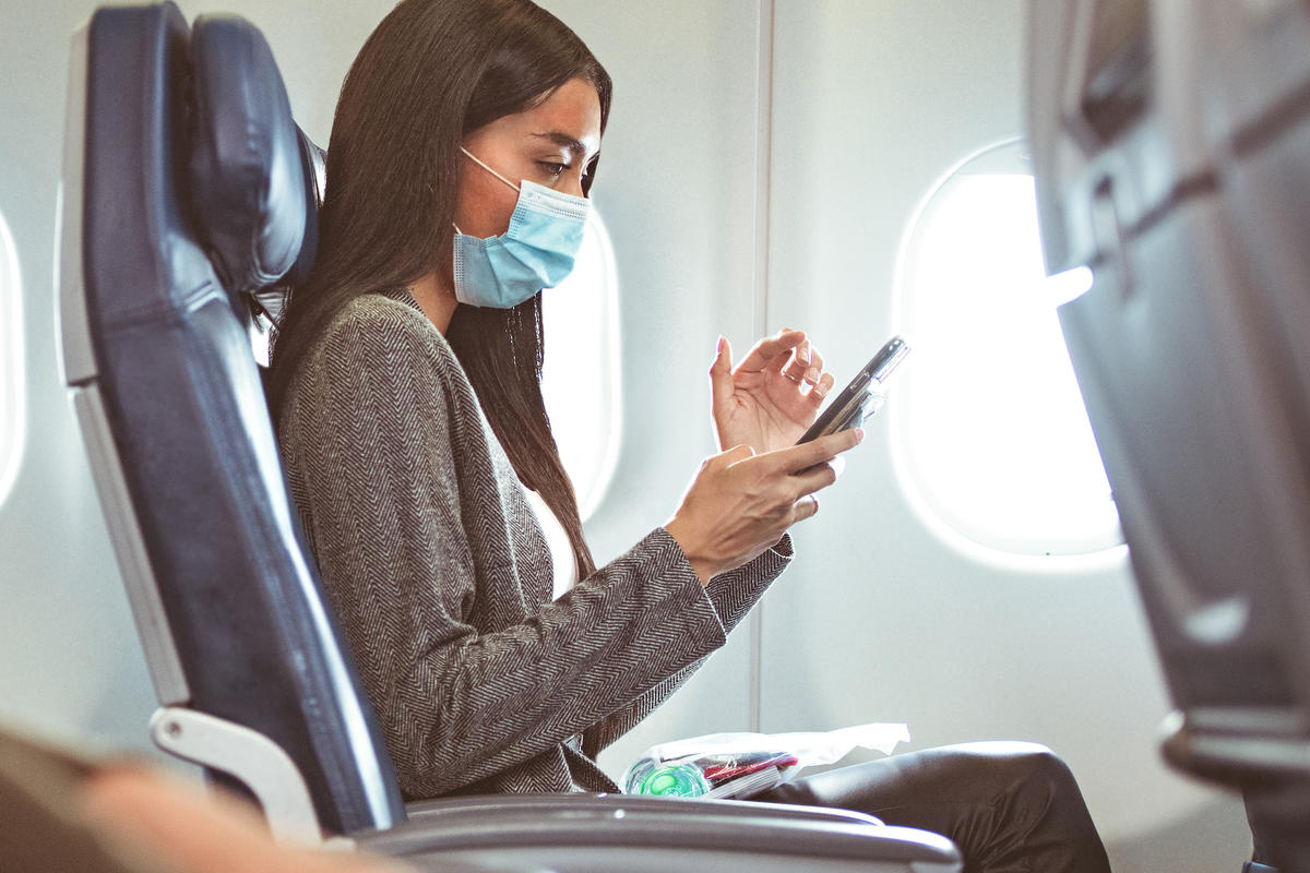 Delta customer in mask at seat with phone