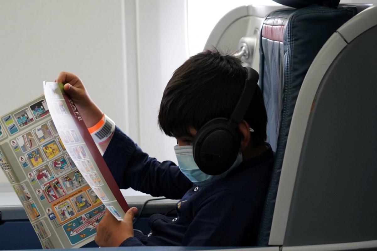 A boy reads a manual on a flight for Afghanistan evacuees.