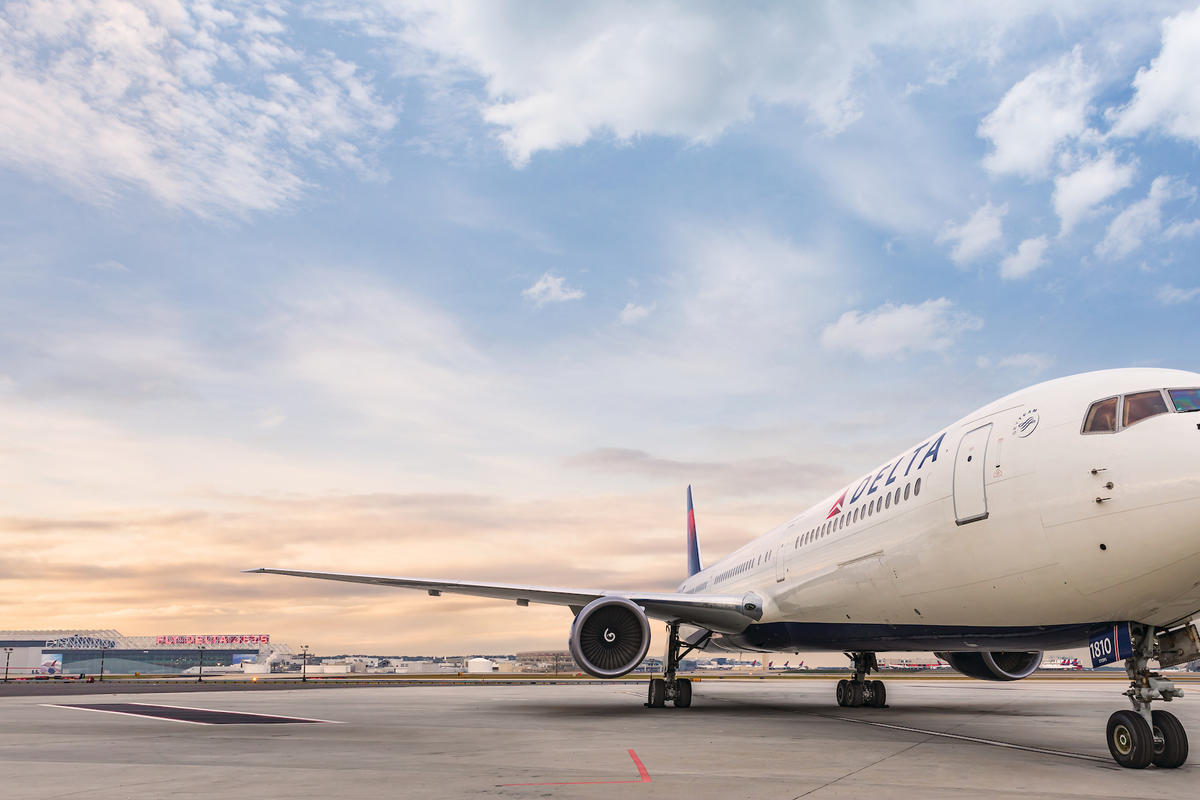 A frontal view of Delta's Boeing 767-400 model sits on the runway while a wisped sky overlooks. 