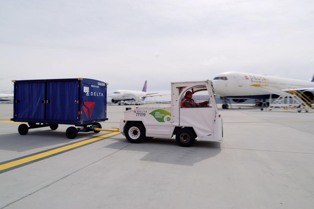 A Delta ramp agent drives an electric bag tractor at Salt Lake City International Airport (SLC).