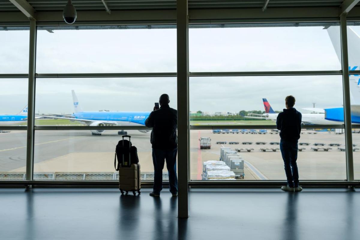 Customers at Schiphol Airport in Amsterdam with Delta and KLM aircraft in the background.