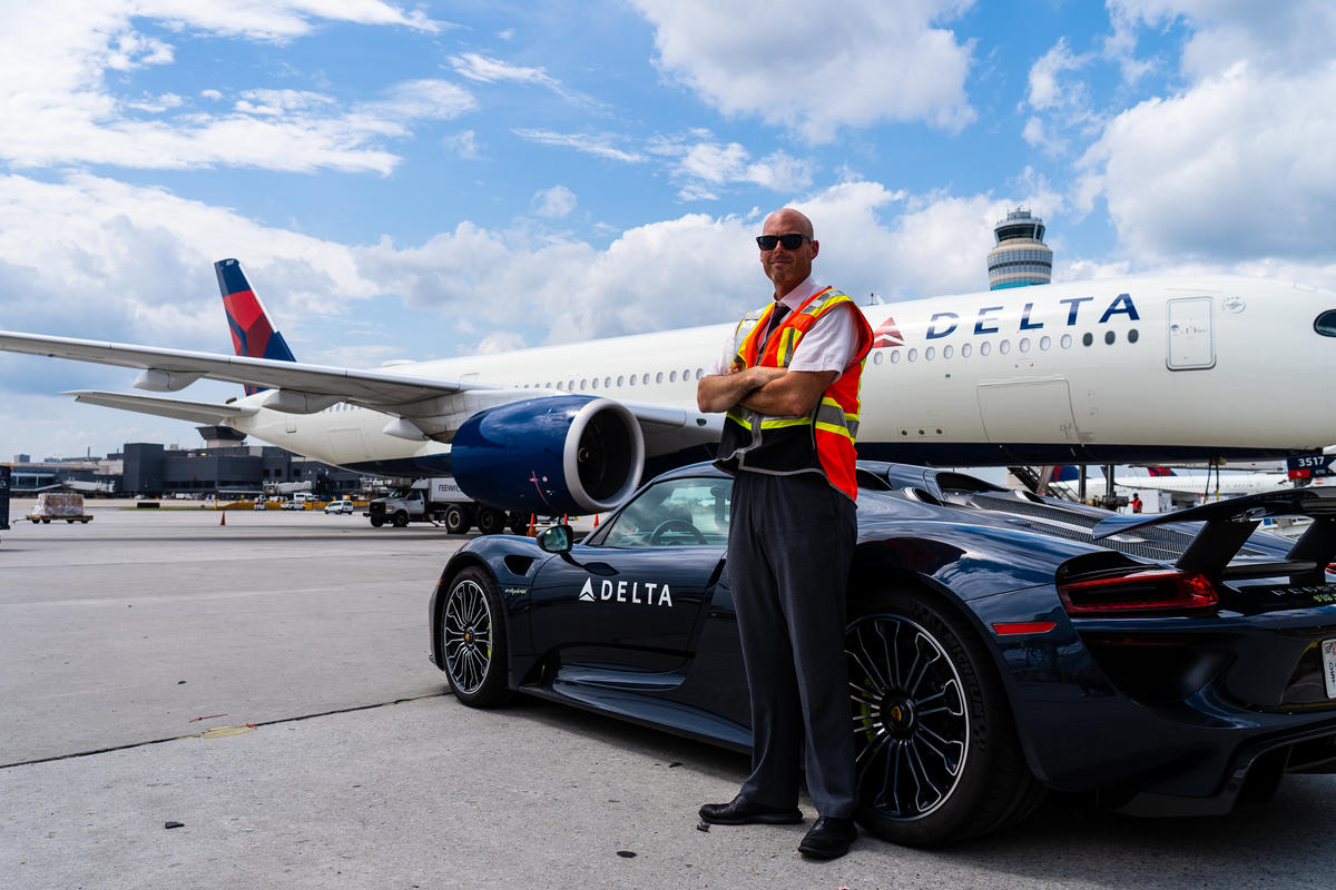 Delta Elite Services Ambassador Dan Lavker waits for a customer next to a Porsche 918 Spyder and an Airbus A350 jet at Hartsfield-Jackson Atlanta International Airport.