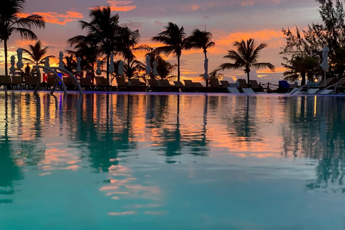 Coconut trees and a pool against a sunrise in Turks and Caicos
