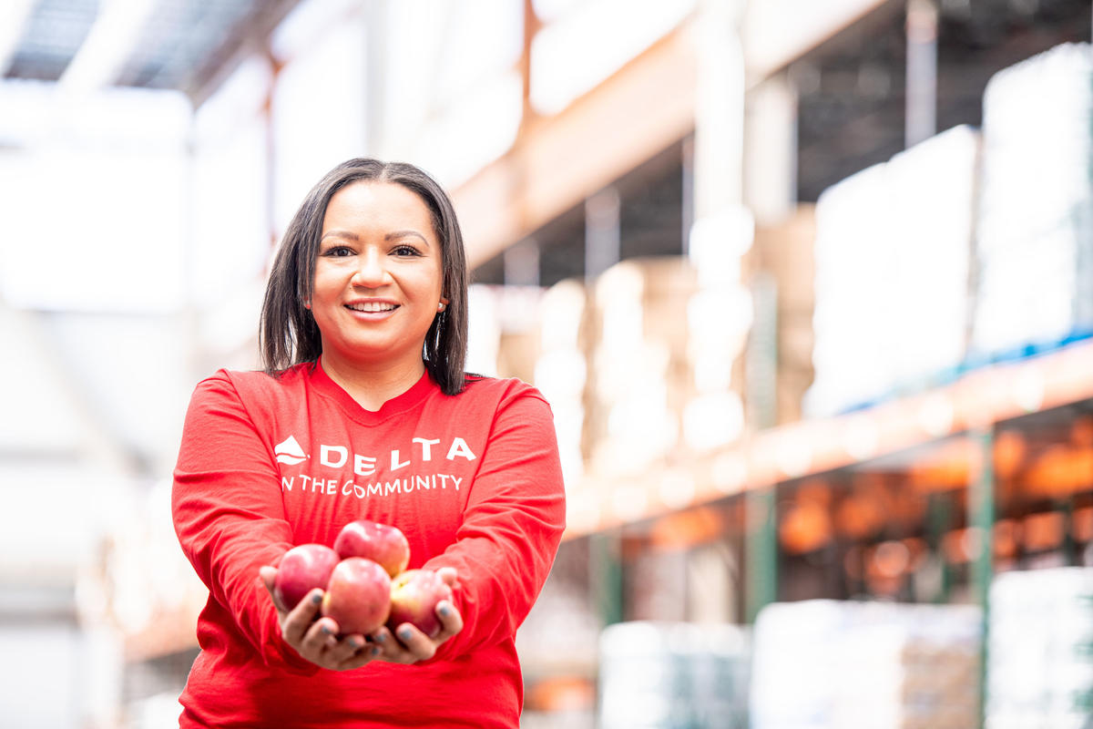 A Delta volunteer holds apples in their hand