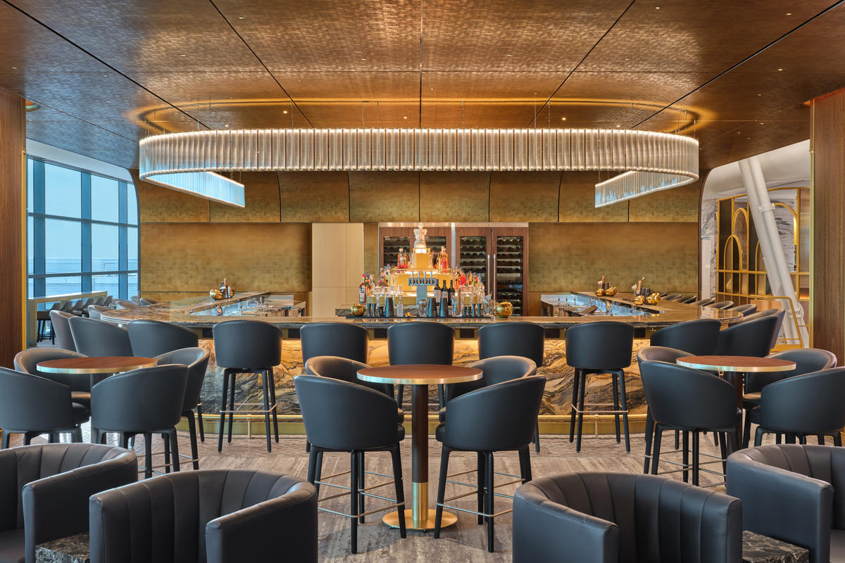 The premium bar at The Delta Lounge - JFK serves elevated takes on classic cocktails and features a standout Art Deco-inspired lighting fixture.