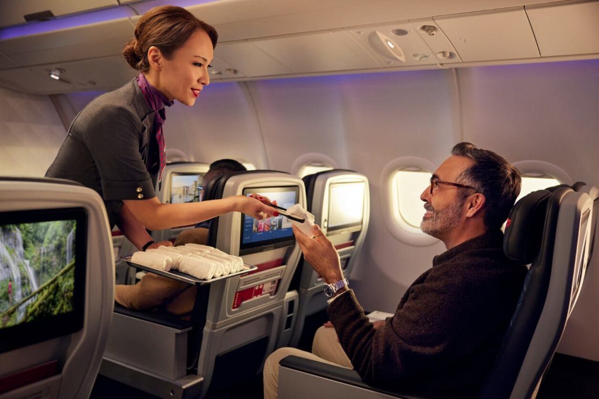 A Delta flight attendant offers a customer a hot towel.