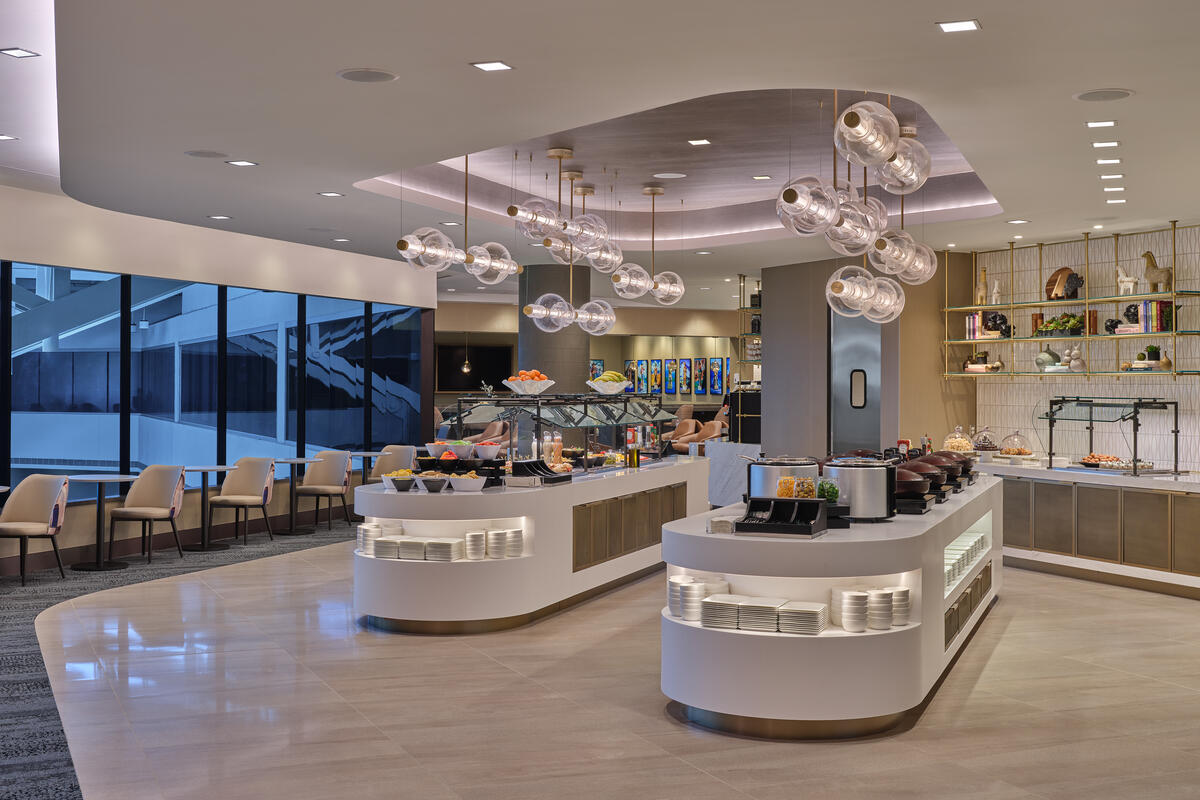 Modern buffet area with curved food stations, hanging globe lights and seating along large windows