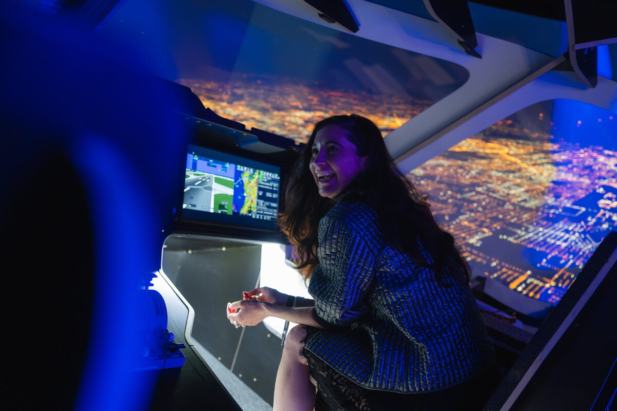 Guest interacts with a flight simulator inside a futuristic, aviation-themed experience.