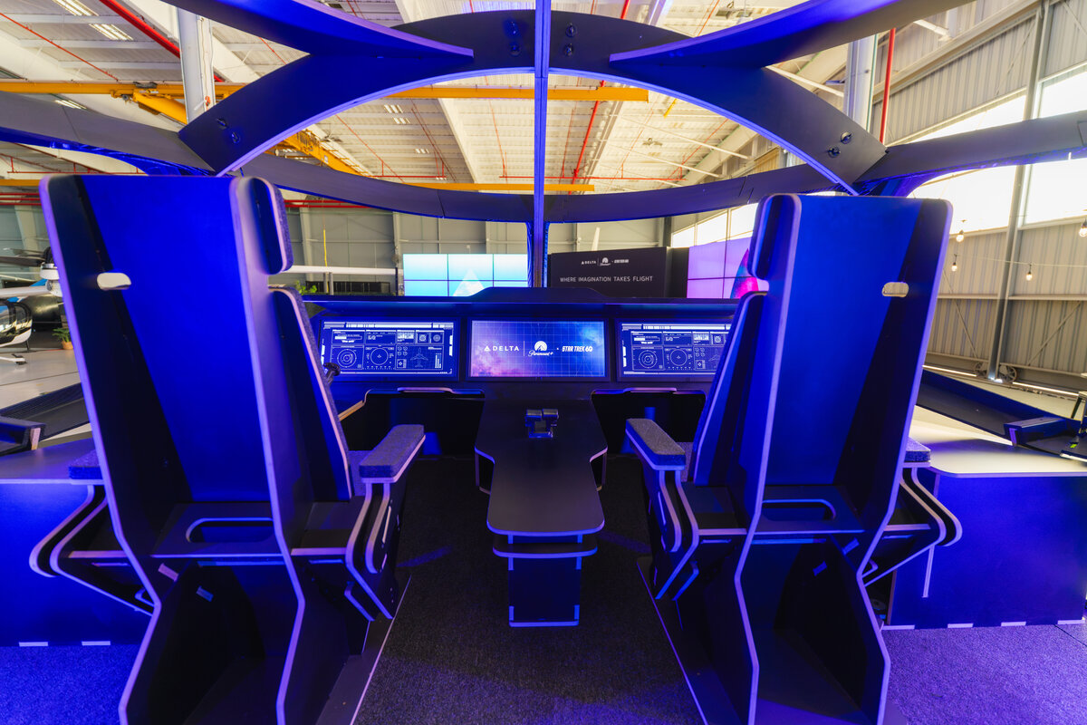 Futuristic flight simulator display with pilot seats and illuminated control panels at a Delta and Star Trek-themed event.