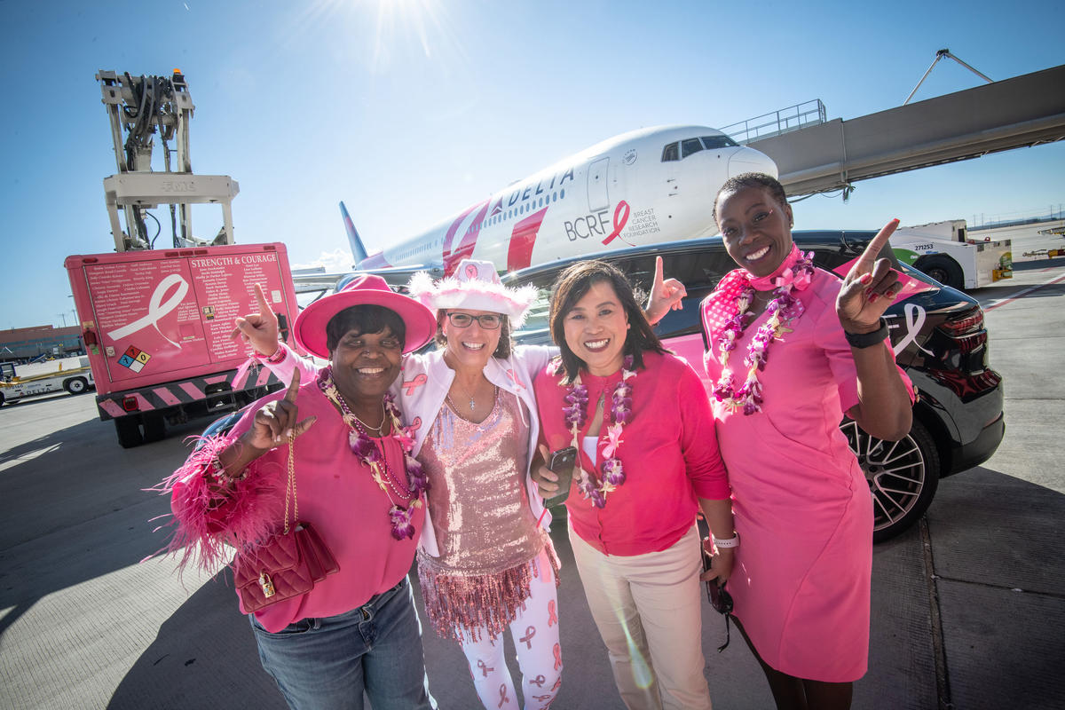 Delta people pose in front of the Breast Cancer One charter plane.