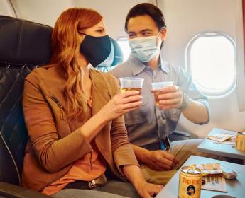 Delta customers with drinks and masks in flight