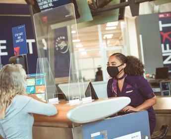 Delta employee and customer at ticket counter with mask