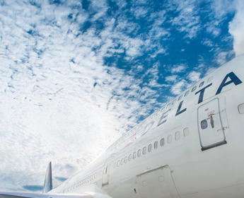 Close up of Delta aircraft with blue skies and clouds